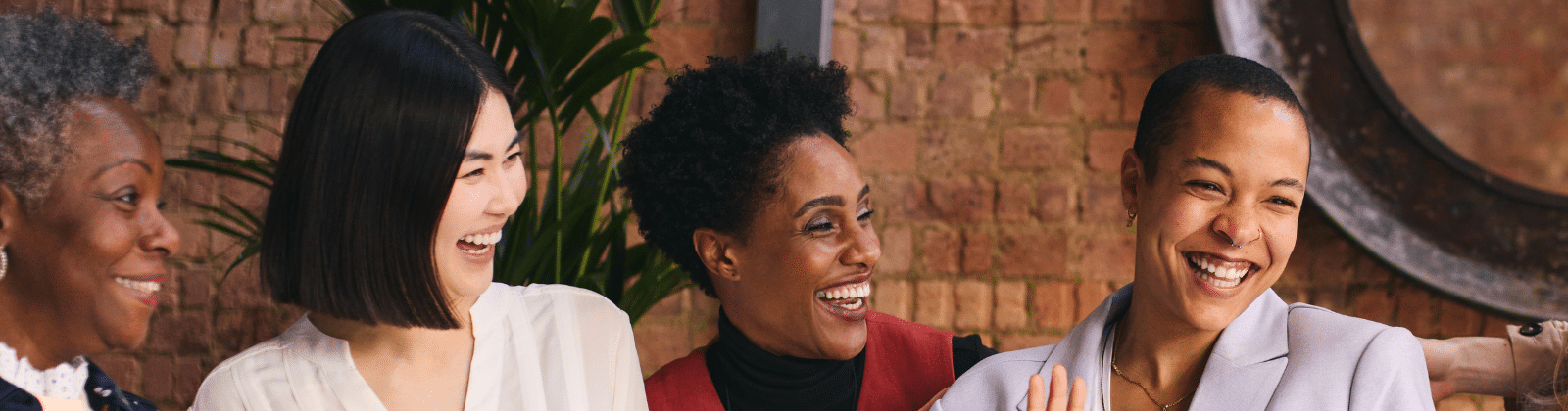 Four women of color laughing together
